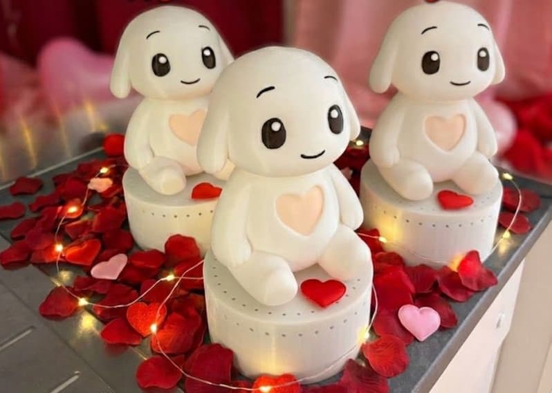 Three white Qluve companion robots sitting on their speaker bases