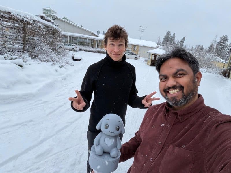 Two members of the Qluve team holding a Qluve robot in the snow during a deployment trip